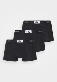 Tris juodų boxer šortų porų su Calvin Klein elastinga juosta, kuri turi balto spalvos prekės ženklą. Minkšta medvilnės medžiaga, prigludęs dizainas.