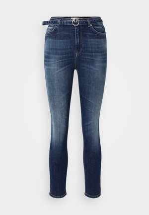 Jeans in denim blu scuro con un design aderente, leggermente sbiaditi, asole per cintura e una fibbia argentata in vita. Stile tradizionale a cinque tasche.