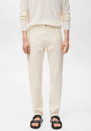 Cream-colored jeans made of denim fabric with a straight-cut design, featuring five pockets and paired with black sandals.