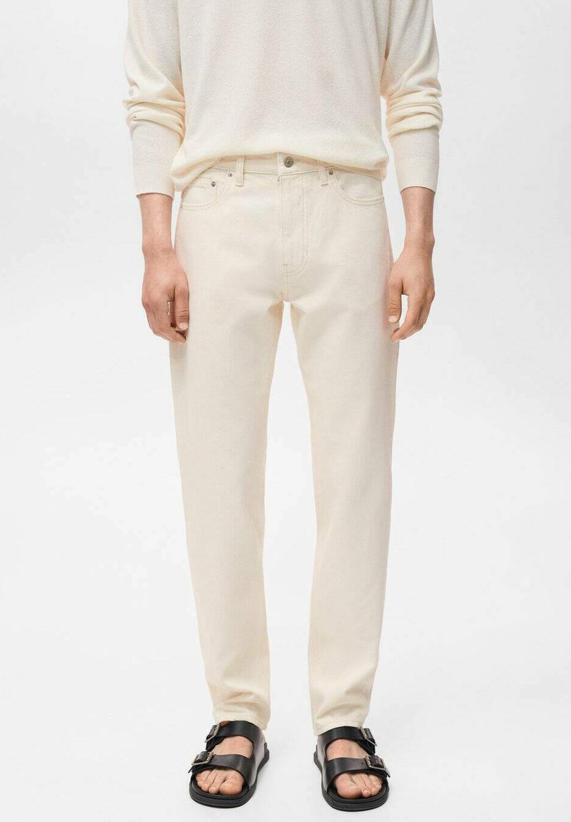Jeans color crema realizzati in tessuto denim con design a gamba dritta, dotati di cinque tasche e abbinati a sandali neri.