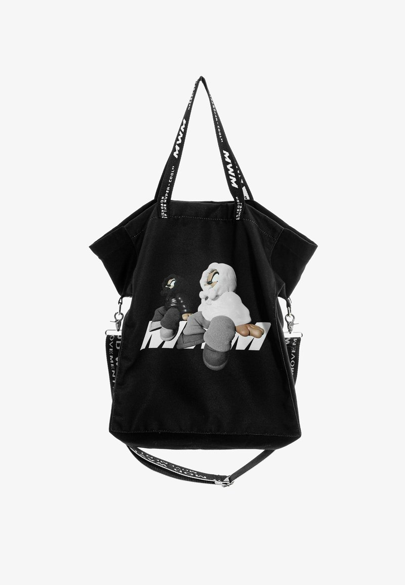 Bolsa tote de lona negra con un diseño gráfico de personajes de dibujos animados, dos asas para llevar y una correa ajustable para el hombro.