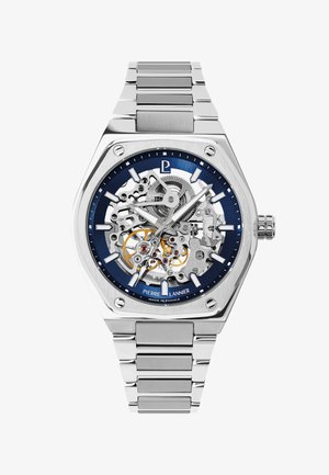 Silver stainless steel wristwatch with skeleton dial showing gears, blue outer ring with hour markers, and silver link bracelet.
