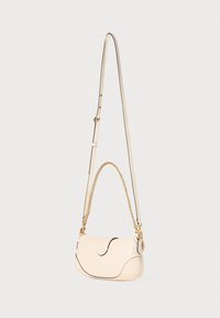 Leather handbag in soft cream color, curved design with contrasting black stitching, adjustable strap combining leather and gold chain accents.