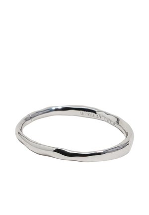 Pulsera rígida de metal plateado retorcido con una forma suave e irregular y un sutil grabado de la marca en el lado exterior.