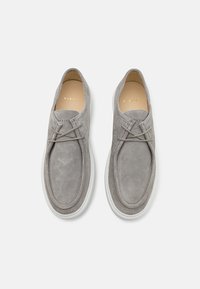 Grå semsket slippers med en avrundet tådesign, med en enkel kryss-lisse detalj og en hvit gummisåle.