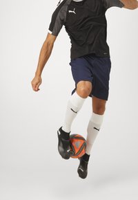 Black and gray short-sleeve jersey, blue shorts, white socks, black soccer shoes, dribbling an orange and black soccer ball, dynamic pose.