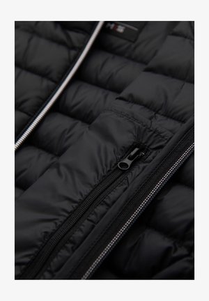 Zwarte pufferjas met een gevoerd ontwerp, voorzien van een centrale rits en ritsen opzij, gemaakt van glad, duurzaam materiaal.