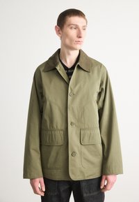 Olive green jacket with a collar, front buttons, and two patch pockets. Features a textured finish and a relaxed fit design.