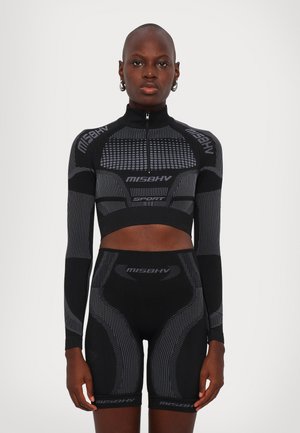 Black athletic set featuring a cropped zip-up long-sleeve top and high-waisted shorts, designed with contrasting textured patterns and logos.