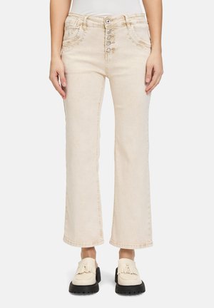 Jean taille haute beige avec fermeture à cinq boutons à l'avant, légèrement évasés aux jambes et poches avant. Texture en denim doux avec un léger délavage.