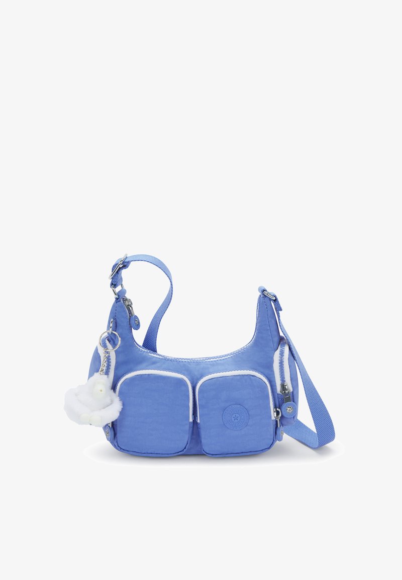 Blaue Schultertasche aus Nylon mit zwei Vordertaschen, einem runden Logo-Patch, einem pelzigen Anhänger und einem verstellbaren Tragegurt.