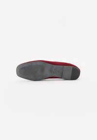 Burgundia suede king, mille sileda ümar pea ja tekstuuriga must kummist välistald, millel on ribaldised detailid haarde tagamiseks.