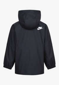 Čierna bunda Nike s kapucňou, elastickými manžetami a logom na chrbte. Hladký, vodoodpudivý materiál a uvoľnený strih.