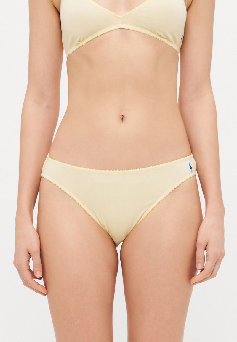 Light yellow bikini bottom made of soft cotton, featuring a scalloped trim, a small embroidered logo, and a classic low-rise cut.