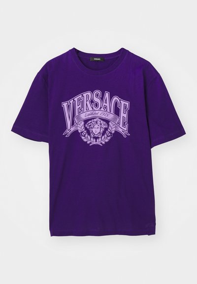 Lilla lühikeste varrukatega T-särk, mille esiküljel on suur "VERSACE Established 1978" tekst ja helelilla Medusa pea logo.