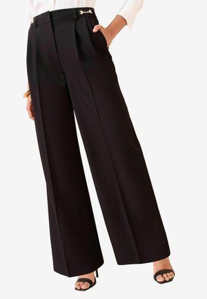 Schwarze weite Hose mit hoher Taille, ausgestattet mit Falten und goldenen Hardware-Details am Bund. Glattes Material mit taillierter Passform.