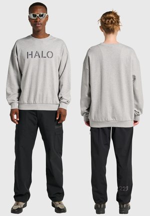 Grå sweatshirt med "HALO" tryk, afslappet pasform; kombineret med sorte cargobukser med lommer og detaljer bagpå; fodtøj med grå og sorte detaljer.