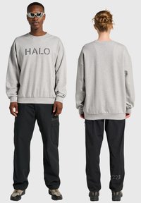 Grå sweatshirt med "HALO"-tryck, relaxed fit; kombinerad med svarta cargobyxor med fickor och detaljer baktill; skor med grå och svarta detaljer.