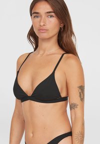 Fekete háromszög bikini felső vékony pántokkal, sima anyagból készült. Minimalista kialakítással, diszkrét fémrészletekkel rendelkezik.