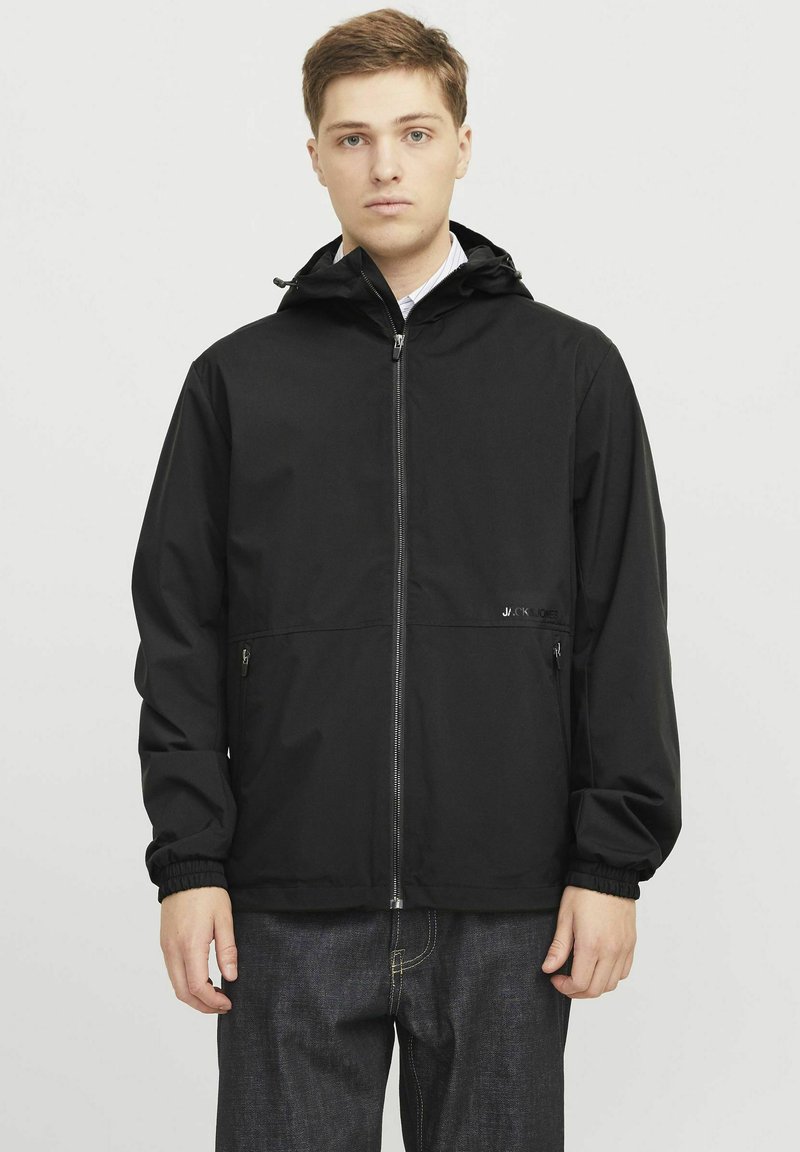 Zwarte hoodie-jack met ritssluiting, elastische manchetten en twee ritssluitingszakken. Gemaakt van soepel, lichtgewicht materiaal. Eenvoudig ontwerp.