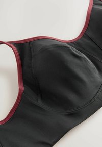 Zwarte sportbh met kastanjekleurige accenten, zachte stof, met beugels, mesh panelen voor ademend vermogen en verstelbare banden.