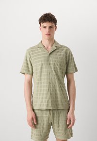 Light green cotton short-sleeve shirt with vertical stripes, button-up front, and a chest pocket. Paired with matching striped shorts.