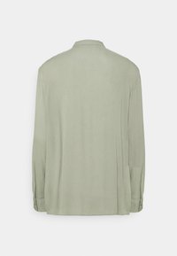 Camicia a maniche lunghe di colore verde chiaro, realizzata in tessuto liscio. Presenta un colletto e polsini con bottoni, con un design a vestibilità rilassata.