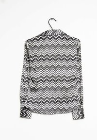 Camicia a maniche lunghe a zigzag in bianco e nero, con colletto e polsini bottonati, realizzata in un tessuto morbido e leggero.