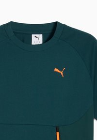 Dunkelblaues Puma-T-Shirt mit Rundhalsausschnitt, orangefarbenem Puma-Logo auf der Brust und orangefarbenem Reißverschlussdetail an der unteren Vorderseite.