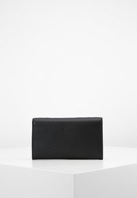 Schwarze rechteckige Clutch mit strukturiertem Oberflächendesign, klaren Linien und einem magnetischen Druckverschluss. Kompaktes Design, das für die Essentials geeignet ist.