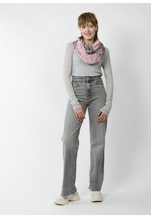 Lichtgrijze lange mouwen top, hooggewaisted grijze jeans en een roze patroon infinity sjaal met cartoonmotieven. Zachte stof en een relaxed fit.
