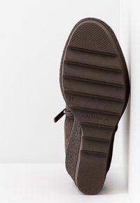 Bottine en daim marron avec semelle en caoutchouc texturé, dotée d'une fermeture éclair sur le côté et d'un talon renforcé. Taille marquée 37.