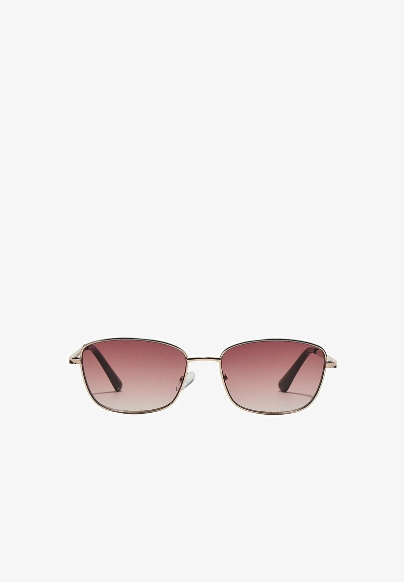 Lunettes de soleil rectangulaires avec une fine monture en métal doré et des verres dégradés teintés rose, embouts de branches noirs visibles, centrées sur un fond blanc.