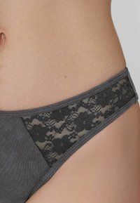 Ropa interior gris con un panel de encaje floral en la parte trasera, con una textura de tela suave y una cinturilla elástica.