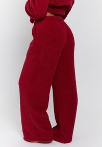 Burgunderfärgade fleecbyxor med ett mjukt, texturerat tyg. Rakt ben-design, elastisk midja och sidofickor. Mysig och varm look.