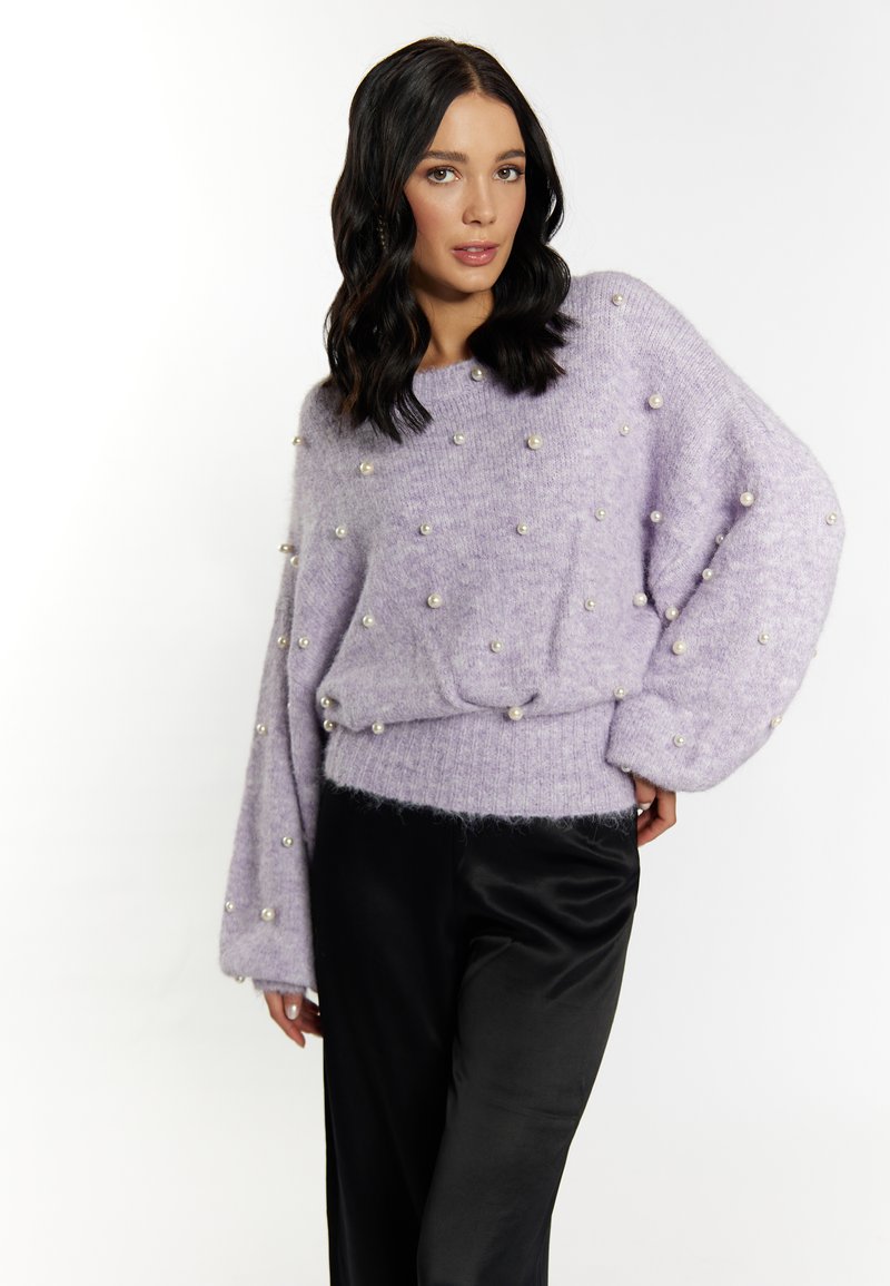 Pulover tricotat lavandă cu accente de perle, mâneci largi și tiv cu nervuri. Asortat cu pantaloni din satin negru neted, creând texturi contrastante.