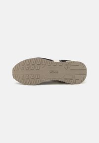 Black athletic shoe sole with a textured rubber surface; features a wave pattern and a textured beige heel for grip and durability.
