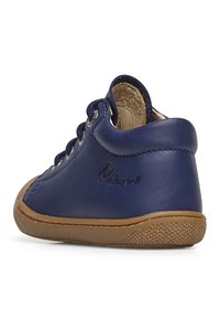 Mörkblå lädersko med tan gummisula. Har snörningsdesign, rund tå och präglad logotyp på sidan. Mjuk foder synligt.