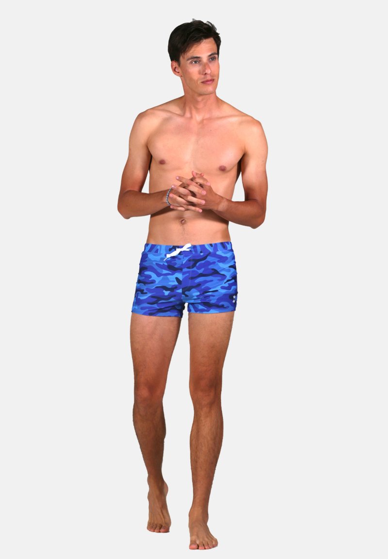 Shorts de bain en camouflage bleu avec une coupe ajustée et un cordon blanc à la taille. Texture lisse, longueur mi-cuisse, sans accents supplémentaires.