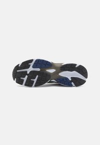Sole di scarpa sportiva in bianco e nero con un motivo in gomma testurizzata per grip, caratterizzata da accenti blu e una soletta stampata per l'ammortizzazione.