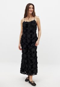 Vestido negro con bordado floral y tirantes ajustables, que presenta una silueta larga y fluida con patrones de rosas texturizados en todo su diseño.