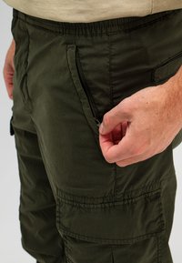 Olijfgroene cargo-broek met een elastische tailleband, uitgerust met een ritssluiting aan de zijkant en gemaakt van duurzaam, lichtgewicht stof.