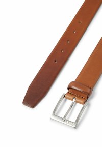 Bruine leren riem met een zilverkleurige metalen gesp. De riem heeft een gladde textuur, een puntige tip en gelijkmatig verdeelde gaatjes voor verstelbaarheid.
