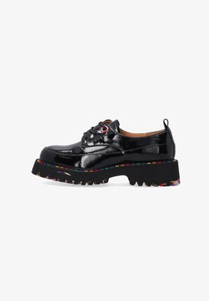 Zwarte patenten leren schoen met dikke zwarte zool, multicolor stiksels langs de rand en ronde veters met rode oogjes.