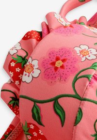 Roza cvetna bikini zgornji del s pompom robom, okrašen s jagodami in cvetjem v belih in rdečih odtenkih, izdelan iz gladkega materiala.
