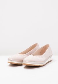 Svetle růžové semišové baleríny s vykrojeným lemem, metalickými akcenty a texturovanou gumovou podrážkou. Zaoblený design špičky pro pohodlí.