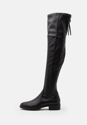Botte noire en cuir montant jusqu'au genou avec un petit talon bloc et une fermeture éclair latérale avec languette, équipée d'une semelle texturée pour une meilleure adhérence.