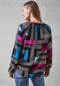Långärmad blus med ett geometriskt mönster i svart, blått, rosa och vitt. Tillverkad i ett mjukt tyg med avslappnad passform.