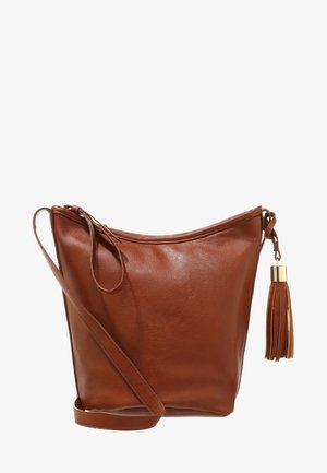 Sac à bandoulière en cuir marron avec une longue sangle et un gland décoratif sur la fermeture éclair, présenté sur un fond blanc.