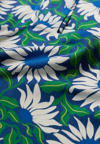 Țesătură albastră cu un model floral, având margarete mari albe, cu centre albastre închise și frunze verzi, creând o apariție vibrantă și texturată.